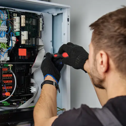 Electrician working on electrical panel representing UK trade businesses using Elite Connector CRM